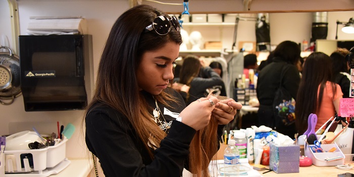 Student looking at parts of a wig during a tour.